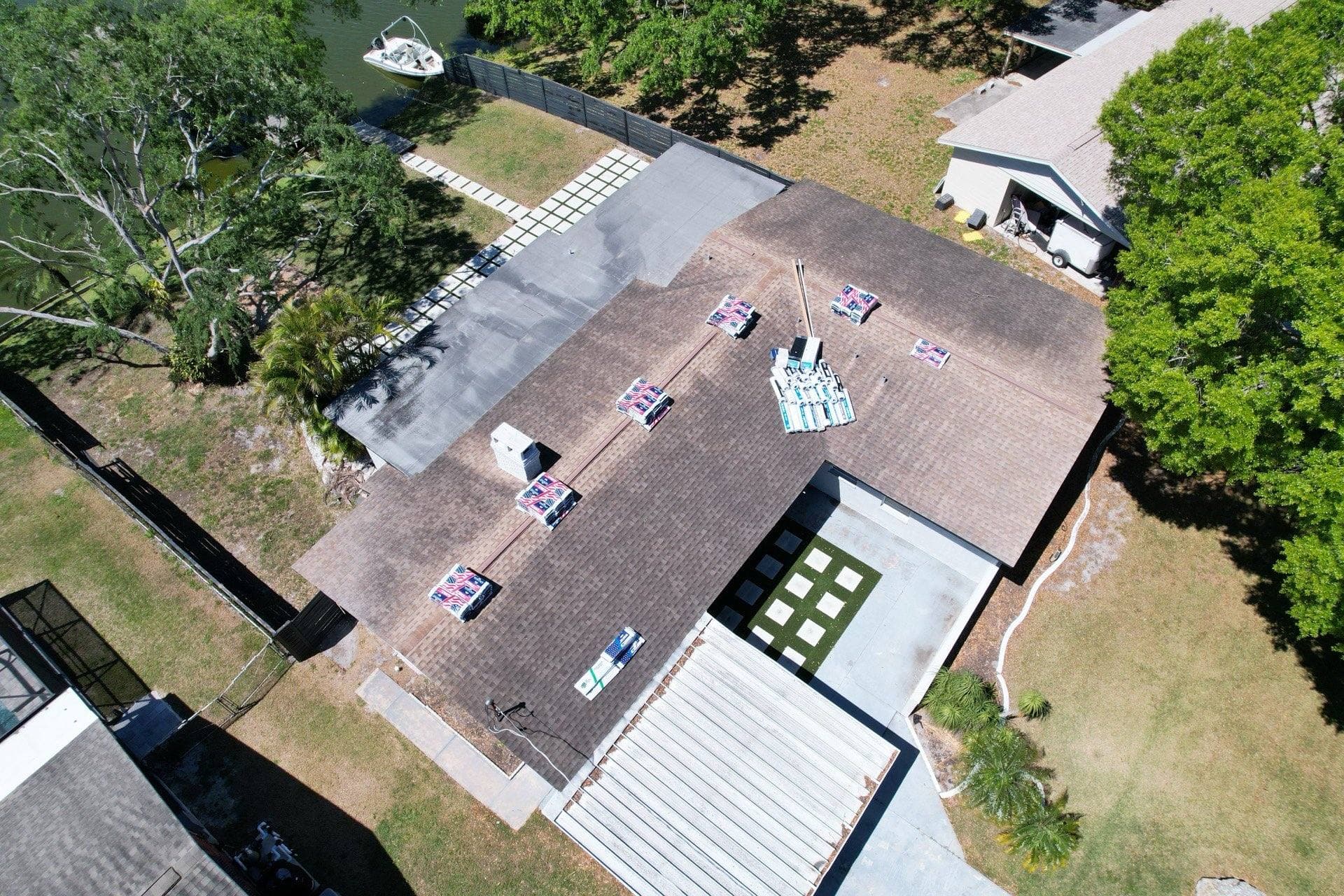 Aerial view of new shingle bundles staged on a worn shingle roof before a roof replacement in Tampa FL