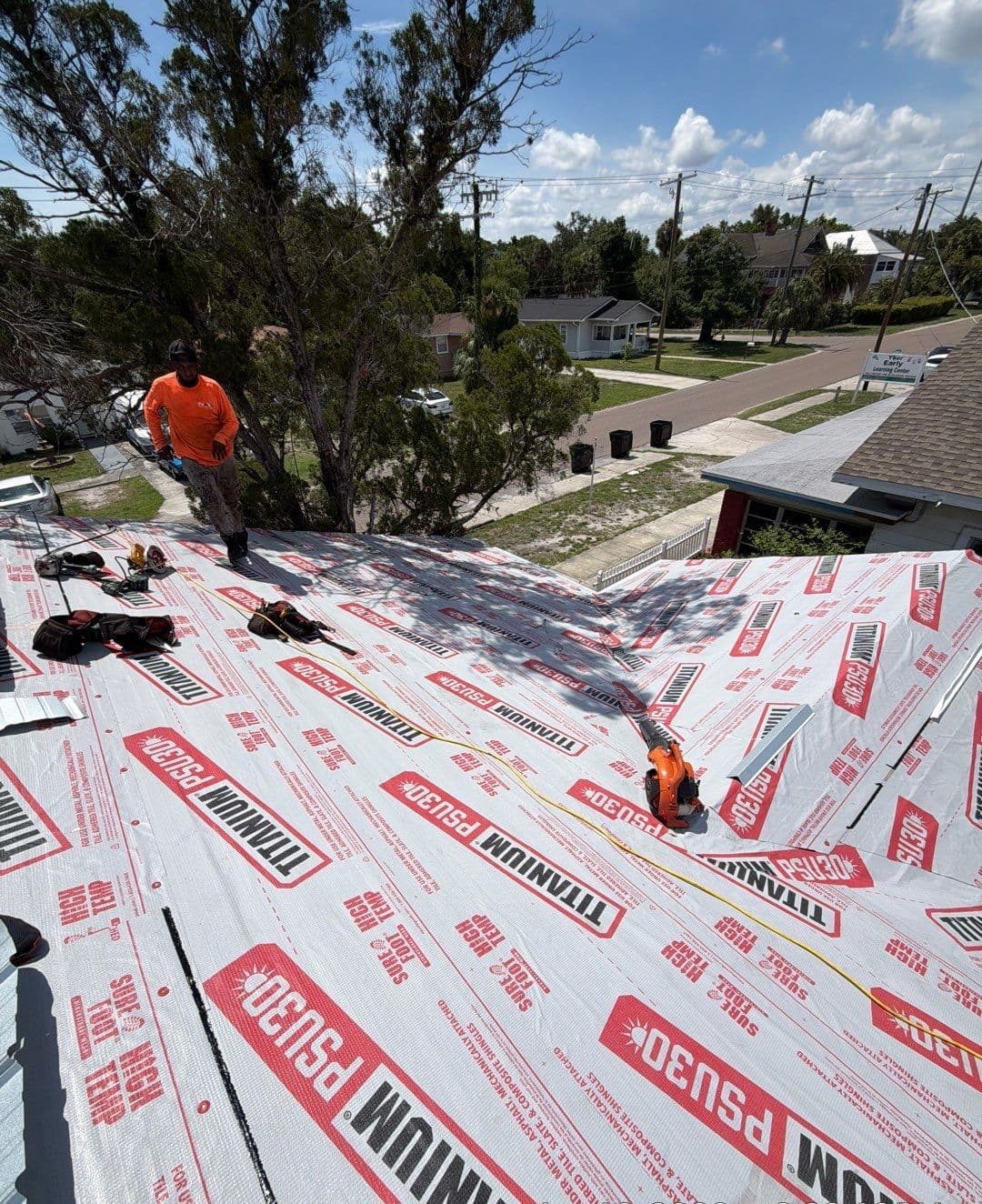 Roofer standing on a fully dried-in roof covered in high-temp synthetic underlayment in Tampa FL