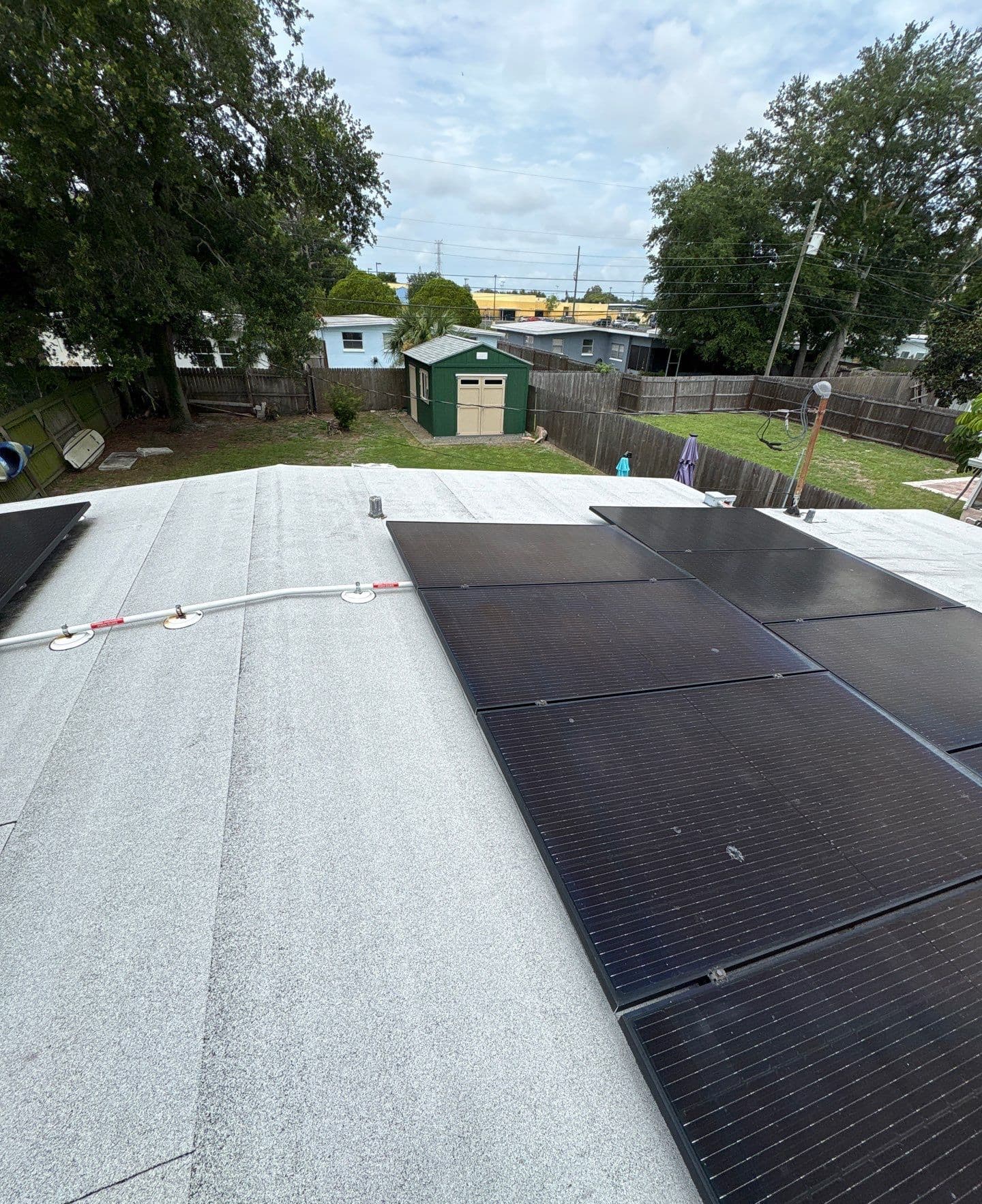 Black solar panels and rooftop conduit on a low-slope granulated roof of a Tampa FL home