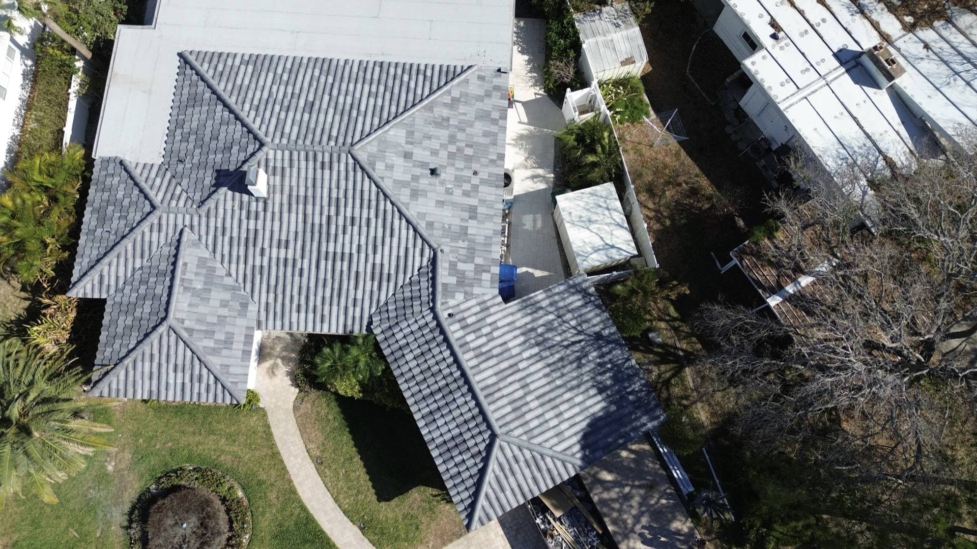 Overhead aerial view of a gray tile roof with hips and a flat roof section on a Tampa FL home