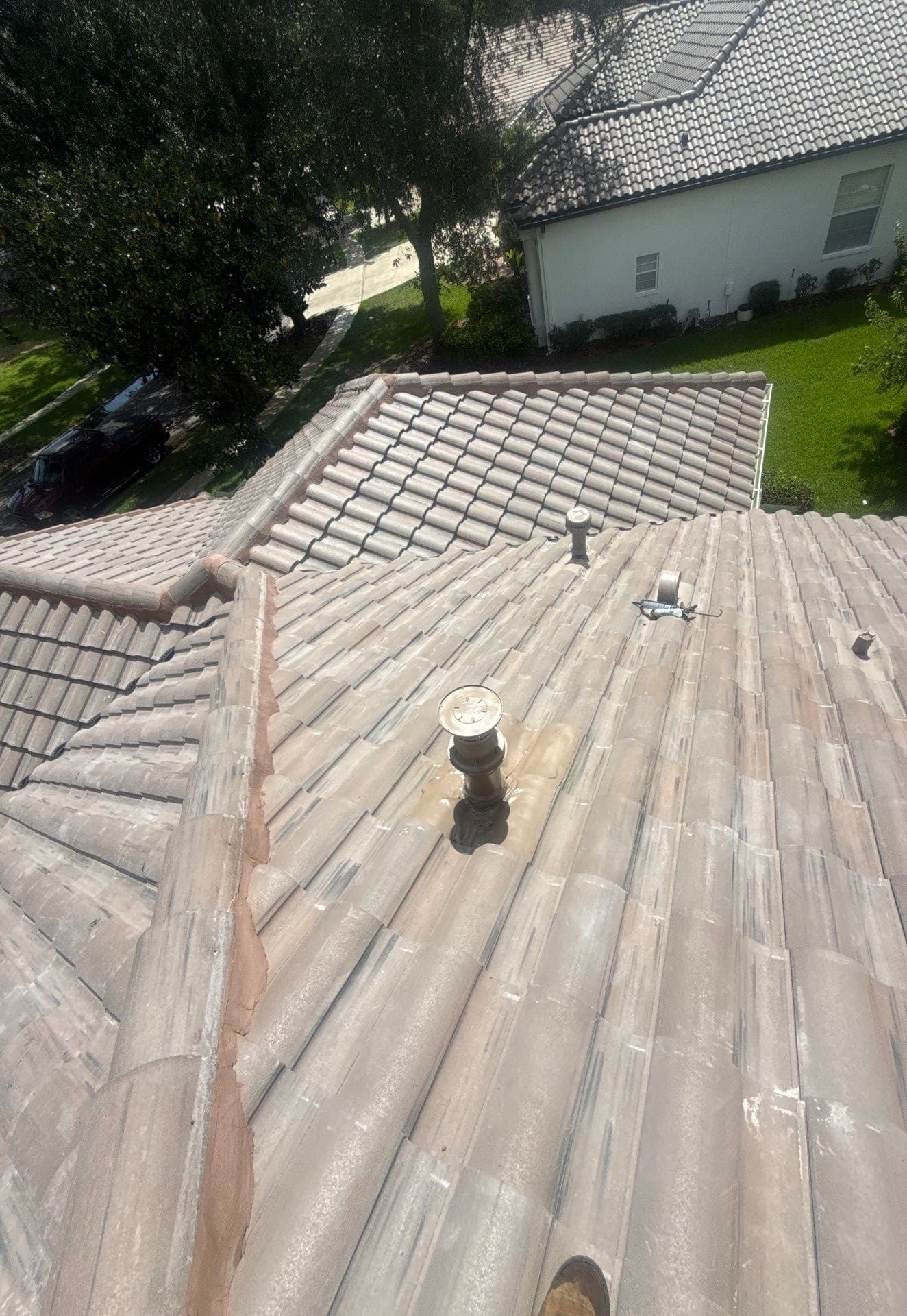 Barrel tile roof with a newly sealed plumbing vent and caulk gun during a tile roof repair in Tampa FL