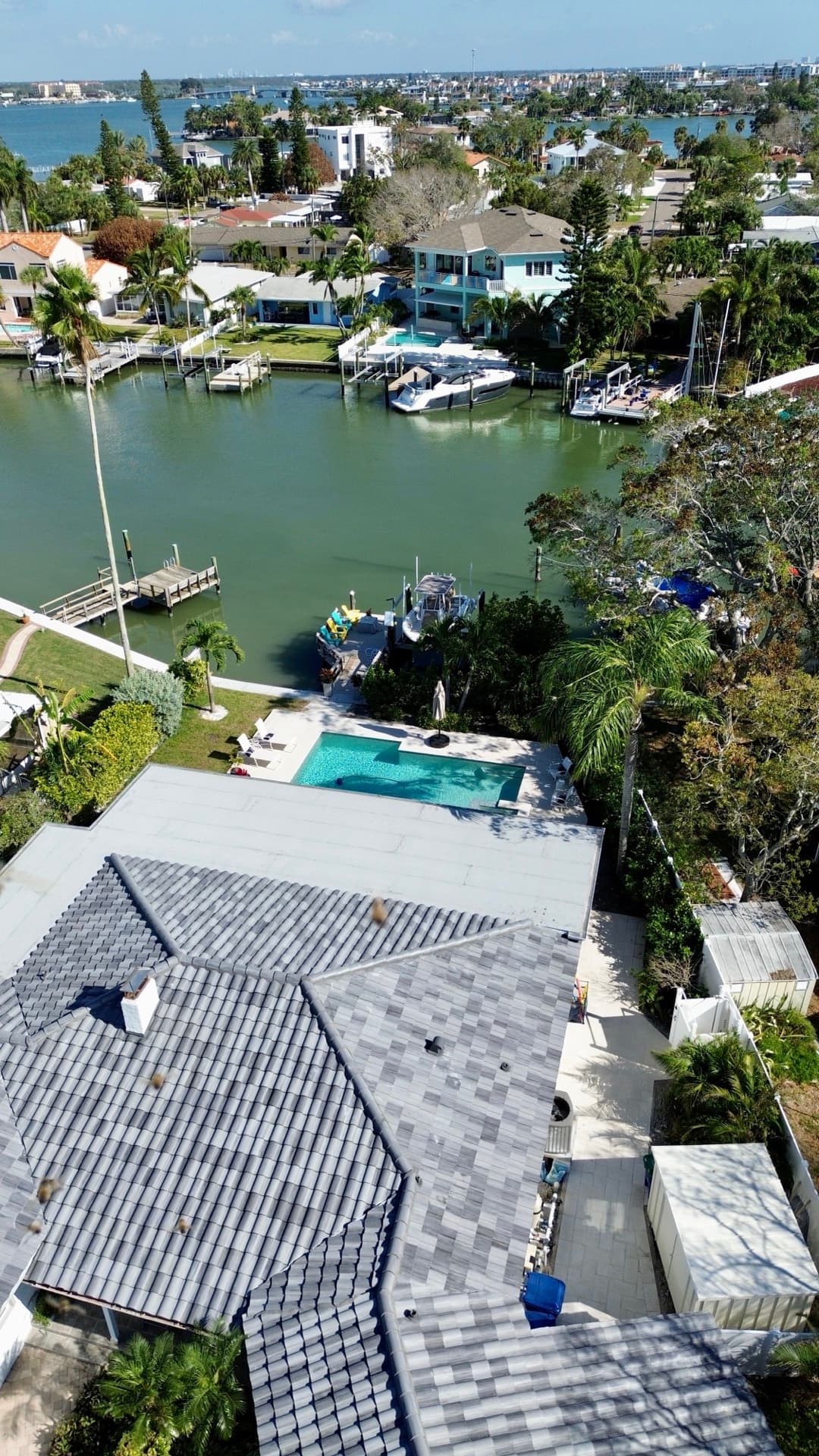 Aerial view of a gray blend tile roof and flat roof section on a waterfront home with pool in Tampa FL