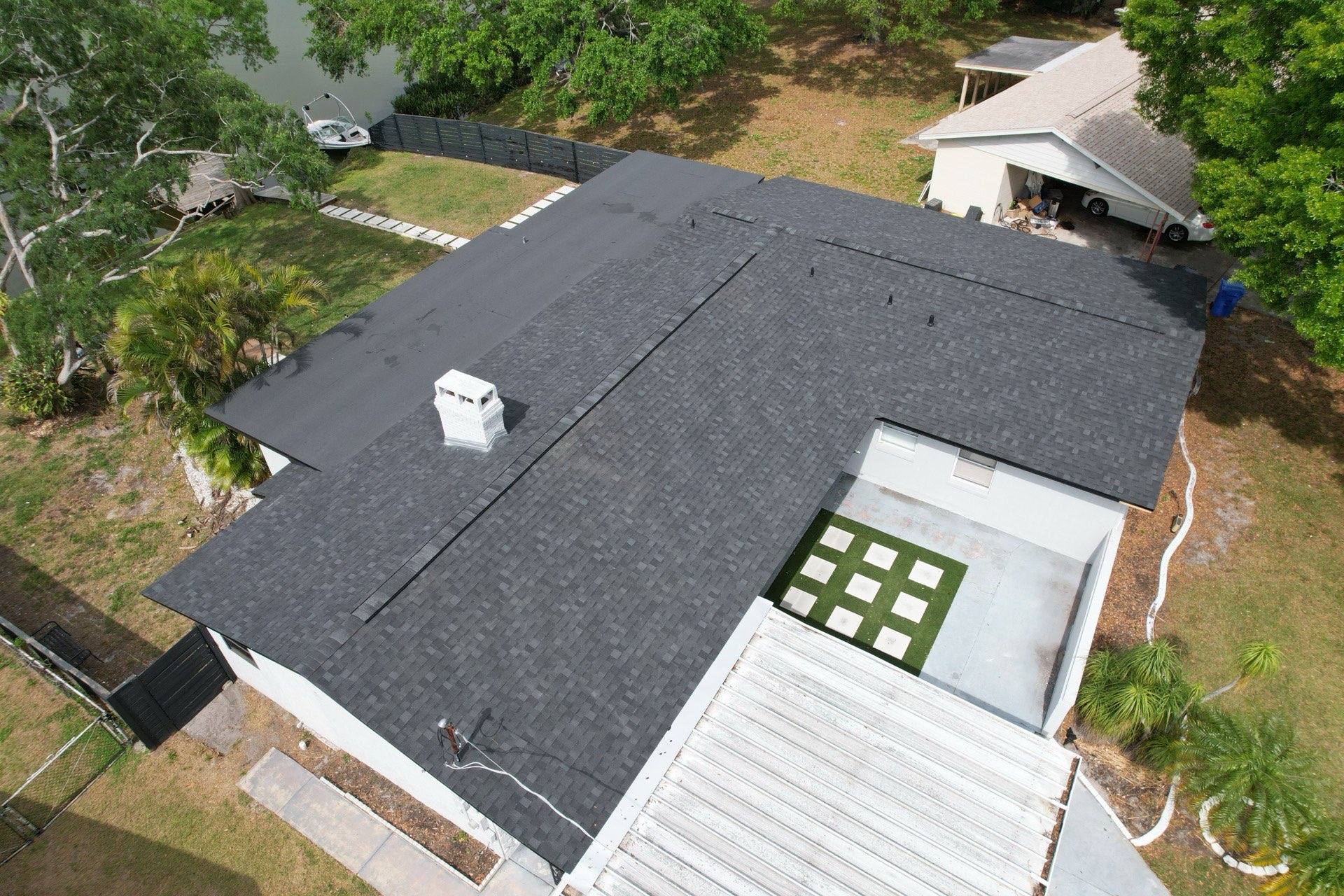 Aerial view of a new charcoal architectural shingle roof with a chimney on a Tampa FL home