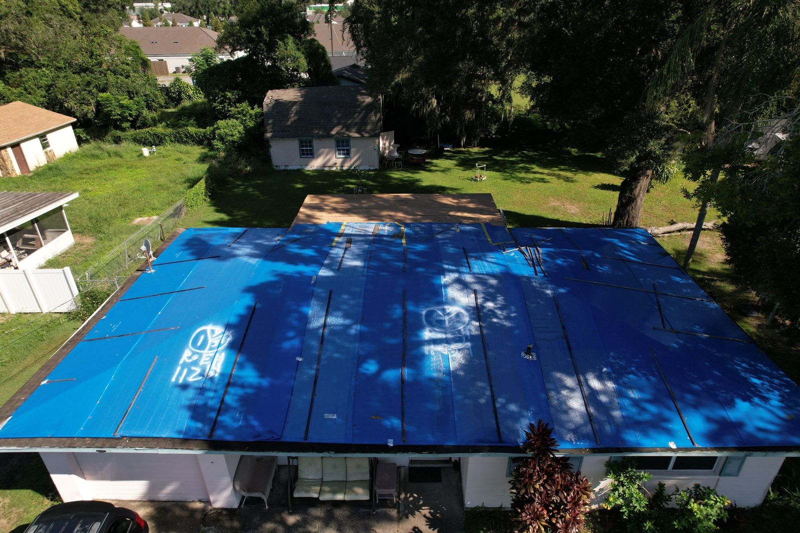 Blue tarps covering a low-slope roof in Brandon before replacement
