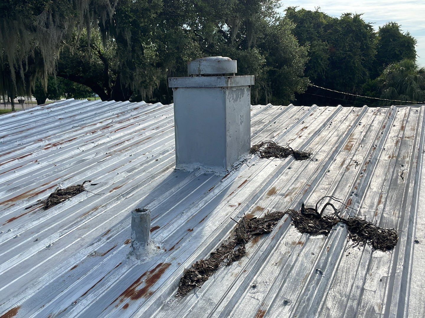 Old metal roof with rust and a furnace stack before replacement