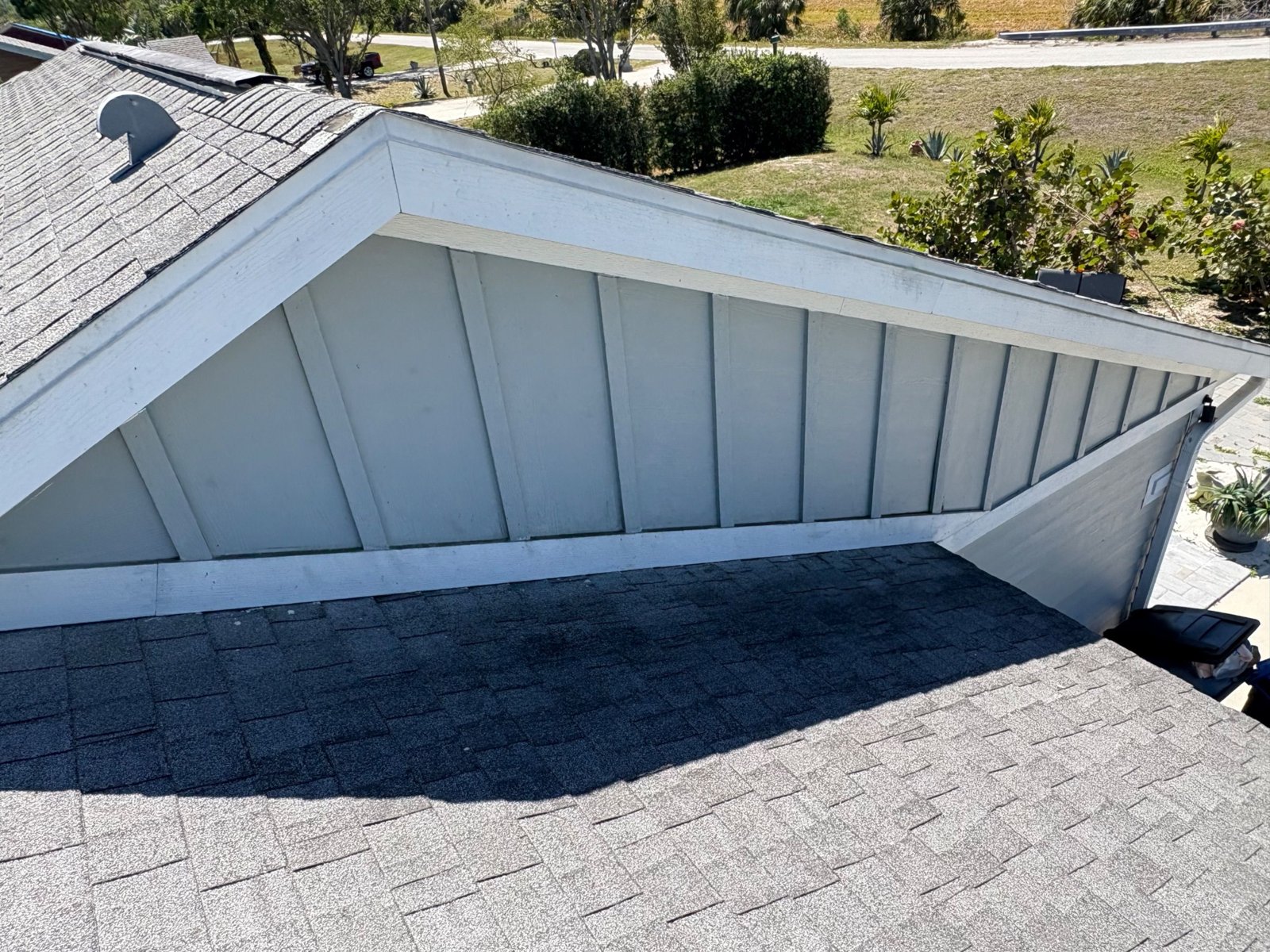 Worn shingle roof meeting a white gable end before replacement in Palmetto FL