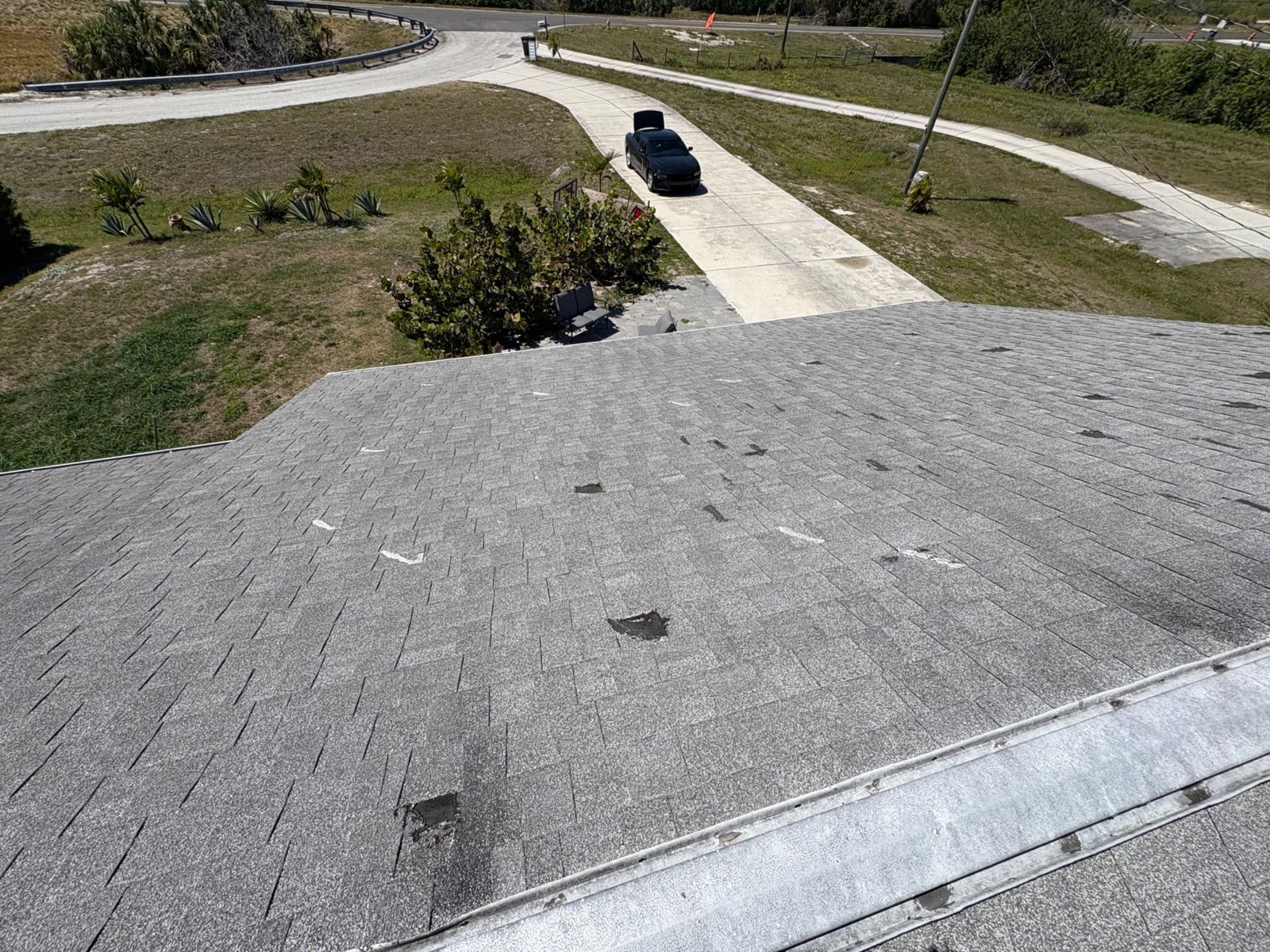 Worn gray shingle roof with exposed tar patches before replacement in Palmetto FL