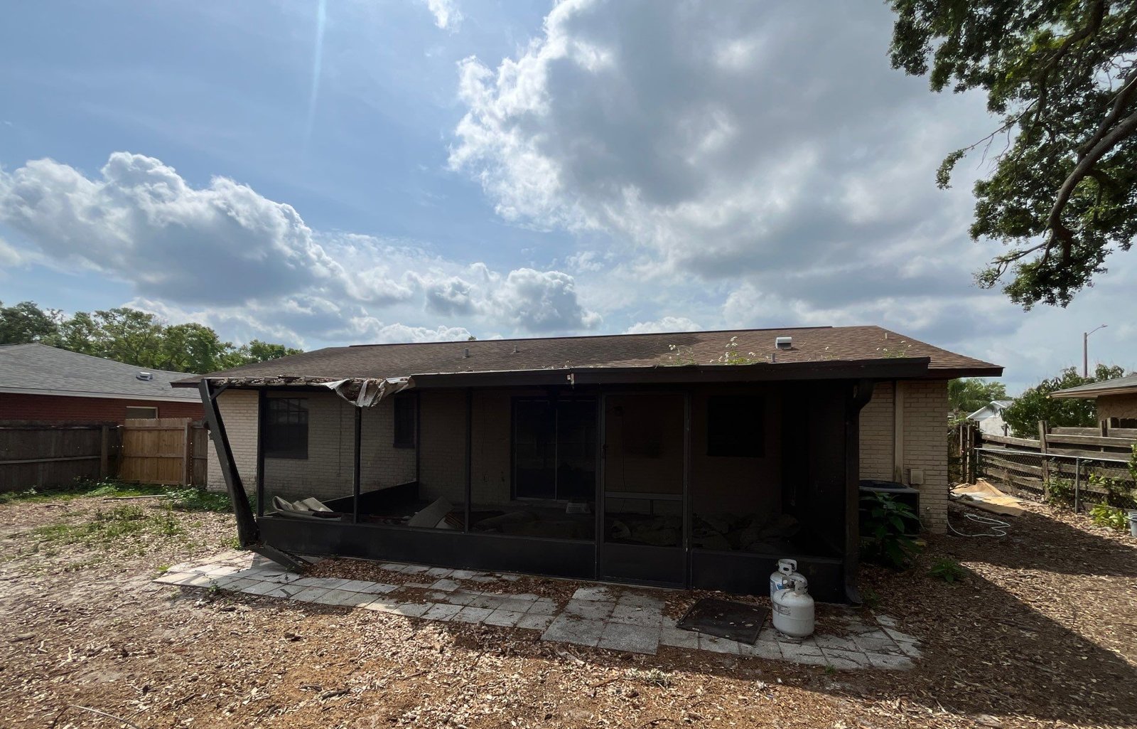Rear of a Seffner FL home with a damaged roof overhang above the screened porch before replacement