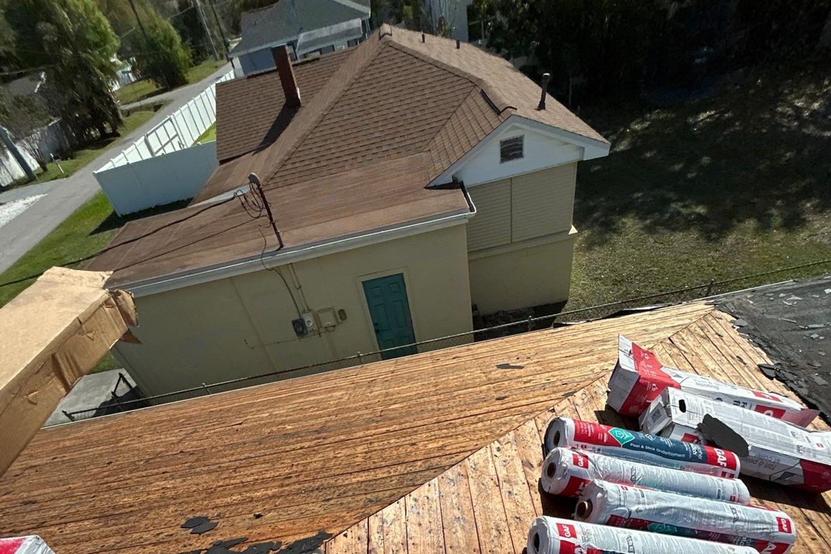 Old shingles torn off down to the wood decking with underlayment rolls staged during a roof replacement in Tampa FL
