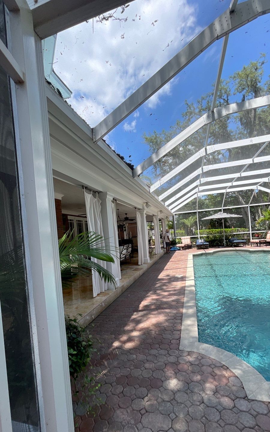 Rear patio roof beside a pool cage before metal roof installation in Tampa