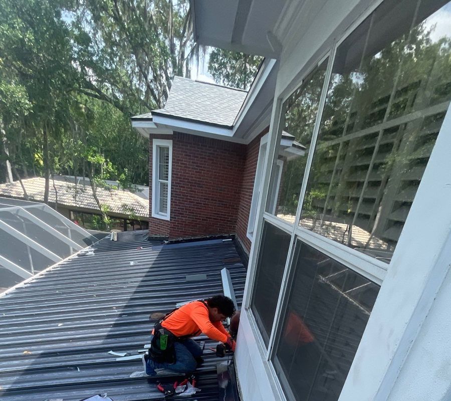 Installer fastening standing seam metal panels on a rear patio roof in Tampa
